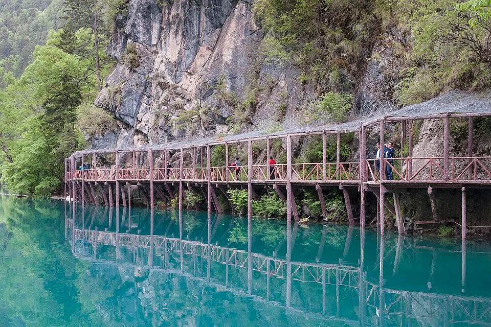 A wooden walkway reflected in the turquoise water of Panda Lake in Jiuzhaigou